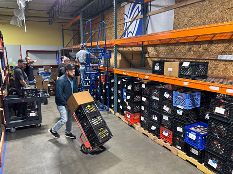 A male volunteer pushing a hand card with crates of donated food