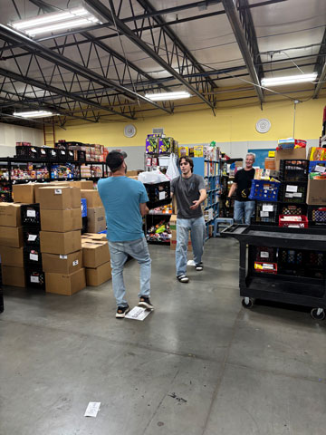 Two volunteers moving boxes and crates of food