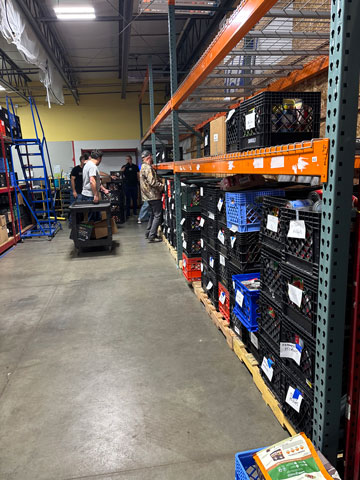 Volunteers stacking crates of food on the Kuna Food Bank shelves